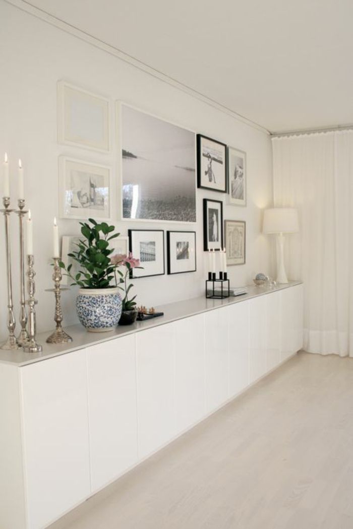 a living room with white walls and pictures on the wall, candles and vases