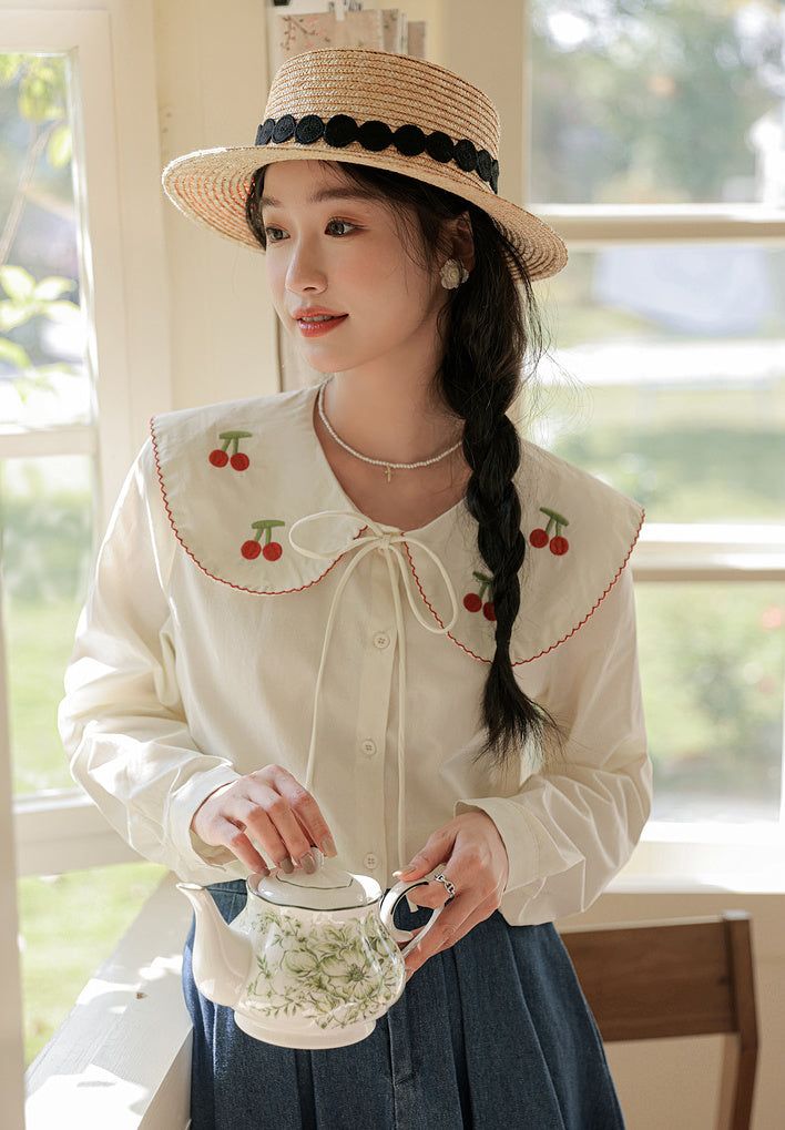 Long sleeve button up shirt with an oversized peter pan collar embroidered with cherries and scallop edges. S: 18" across shoulders, 37" chest, 23" lengthM: 18.5" across shoulders, 38.5" chest, 23" lengthL: 19" across shoulders, 40" chest, 23" lengthXL: 19.5" across shoulders, 41.5" chest, 23" length Cute Collared Shirt For Spring, Cute Collared Fall Shirt, Cute Shirt With Doll Collar For Spring, Cute Collared Shirt For Fall, Cute Doll Collar Shirt For Spring, Spring Lace Collar Button-up Shirt, Casual Blouse With Doll Collar, Casual Blouse With Cute Collar For Fall, Spring Shirt With Lace Collar