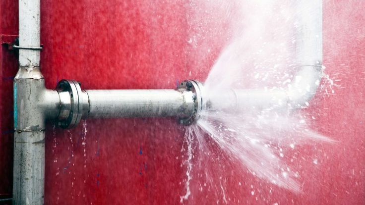 a red wall with a water spout coming out of it