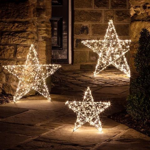 three lighted stars sitting on the ground in front of a building