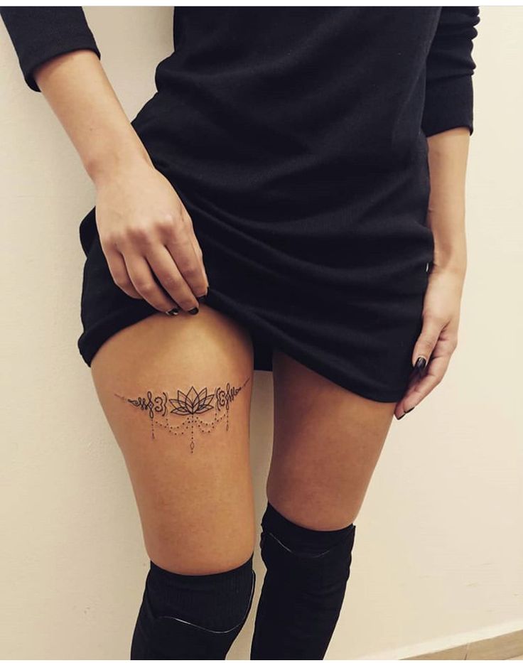 a woman's thigh with tattoos on her legs and knee high socks, standing against a wall