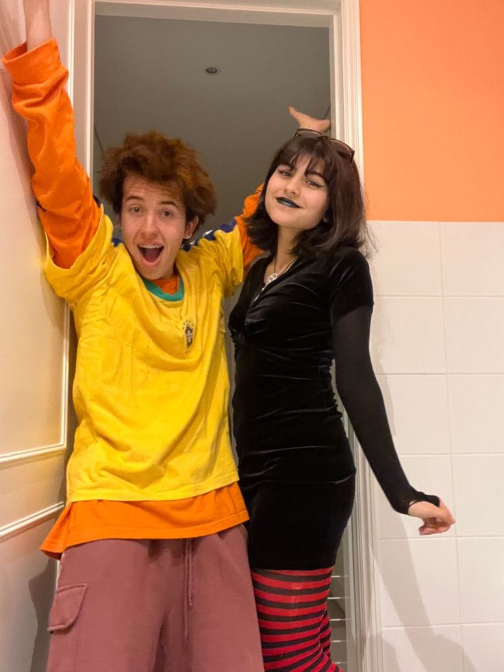 two people dressed in costumes standing next to each other and posing for the camera with their hands up