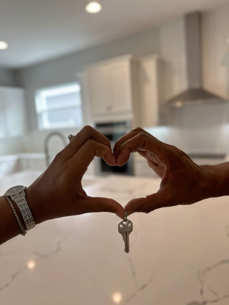 two people making a heart shape with their hands and holding keys in the shape of a heart