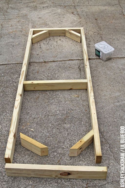 an unfinished bed frame laying on the ground with one end missing and another side missing