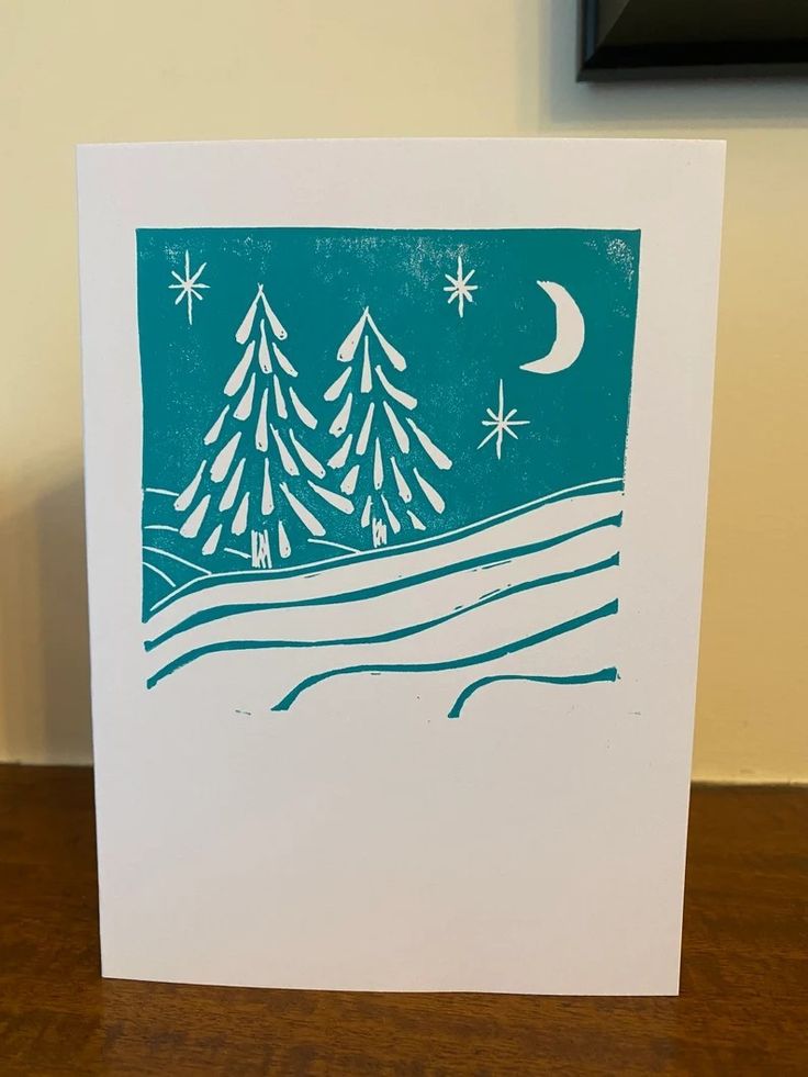 a card with trees and stars in the background on a wooden table next to a wall