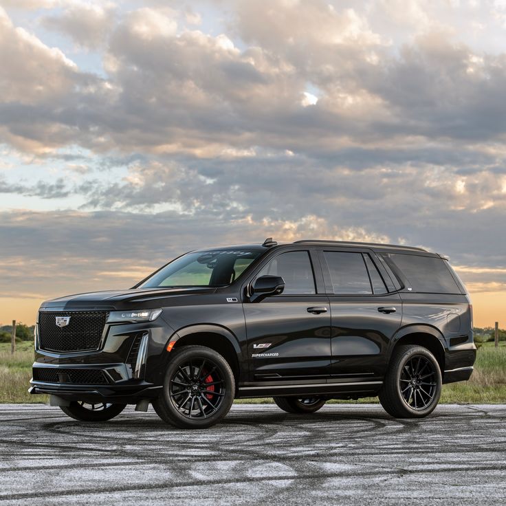 a black suv is parked on the side of the road in front of a cloudy sky