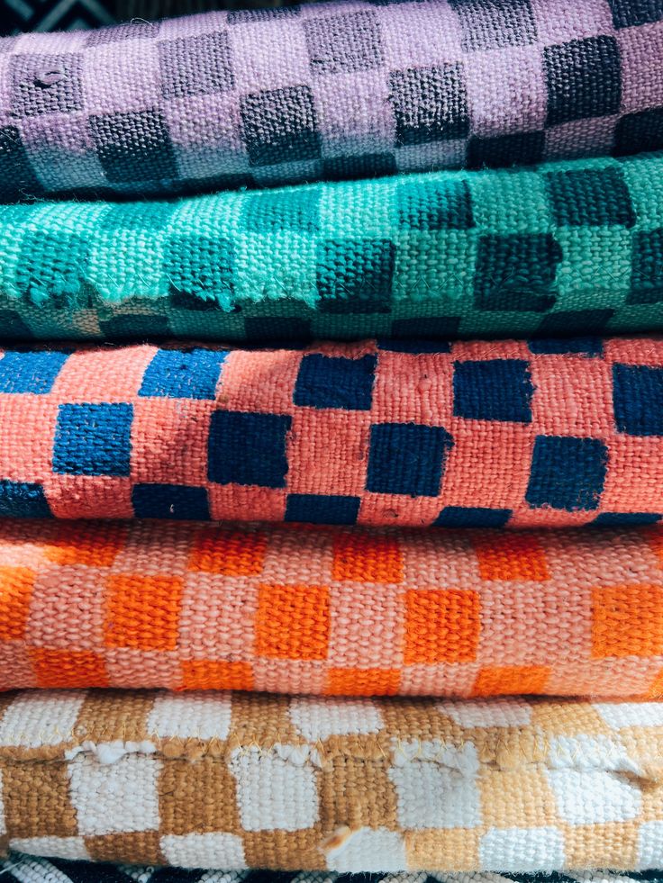 a stack of towels sitting on top of each other in different colors and patterns,