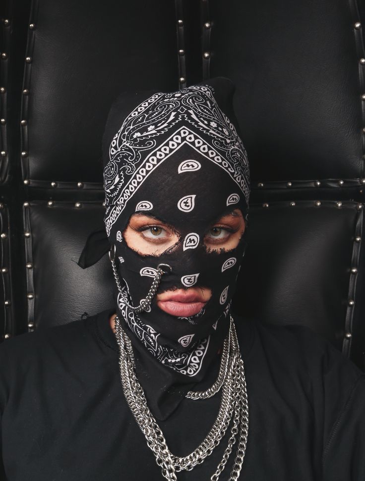 a woman wearing a black mask with chains around her neck and eyes covered by a bandana