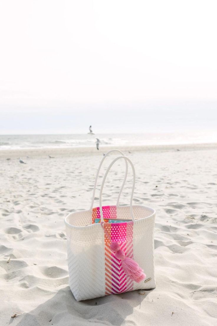 Venture boldly. Bags for making bold moves. These bags are colorful, hand-woven Mexican baskets that bring a bright, authentic style to any occasion. This bag is one of our biggest bags. Playera means "beach" in Spanish and this bag is perfect for beach/pool days. Large enough told hold 4 rolled towels, water bottle, book, phone and more! Our bags are made with durable plastic that lasts a lifetime. Care Instructions: Wipe the bag with a damp cloth and mild soap to remove dirt or stains. You can White Rectangular Bucket Bag For Beach Season, Beach Bag With Braided Handles, White Rectangular Crochet Bag For Beach, Pink Woven Beach Bag, White Handwoven Beach Bag For Travel, Multicolor Beach Bag For Everyday Use, Multicolor Rectangular Bag For Poolside, White Straw Bag For Beach, White Summer Bucket Bag For Shopping