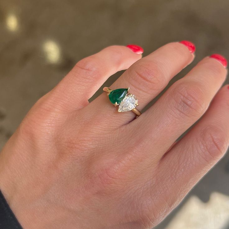 a woman's hand with a green and white diamond ring on her left hand