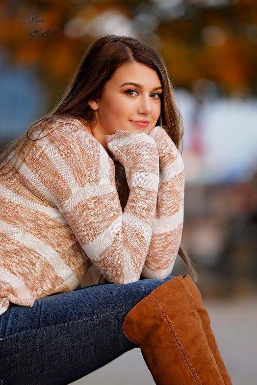 a woman sitting on the ground with her legs crossed and wearing brown knee high boots