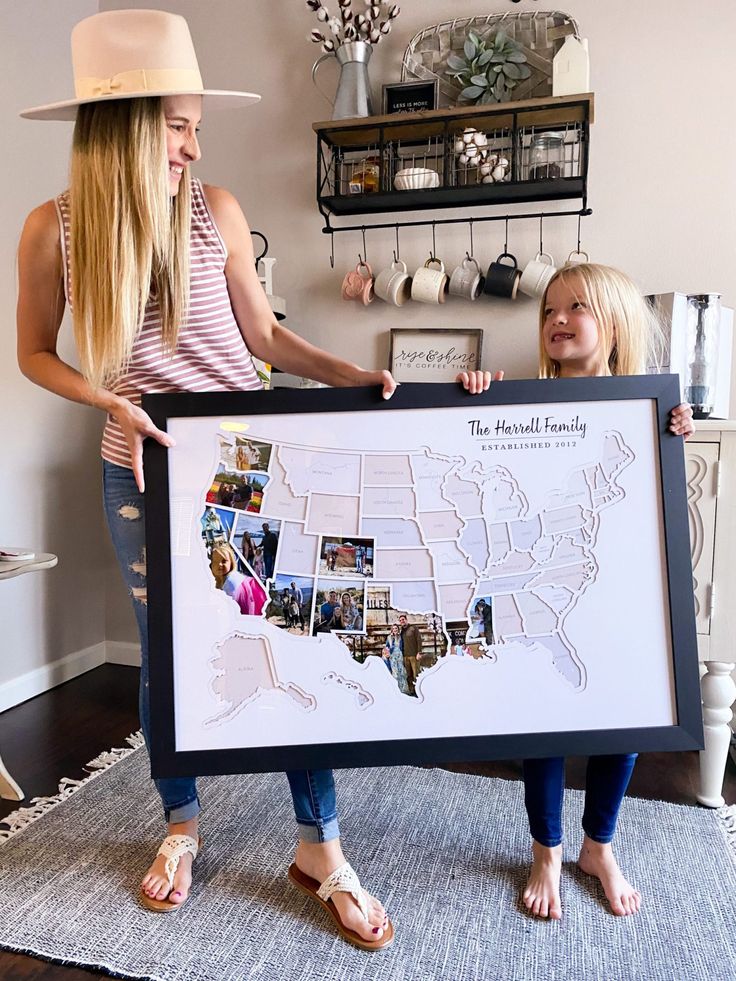 two women holding up a large framed map with pictures on it and the words, the beautiful family