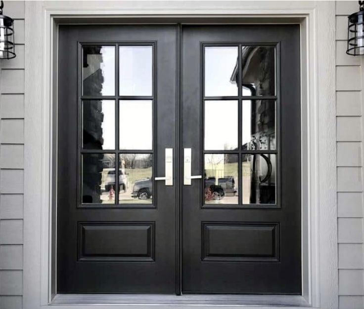 a black double door with two sidelights in front of a house