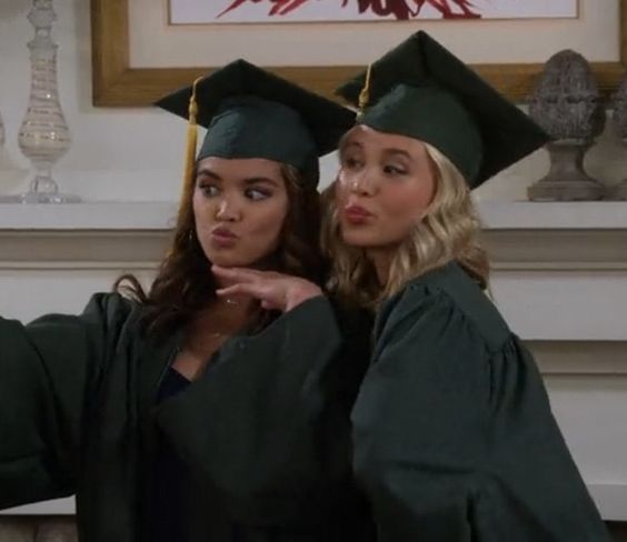 two women in graduation caps and gowns posing for the camera with one pointing her finger