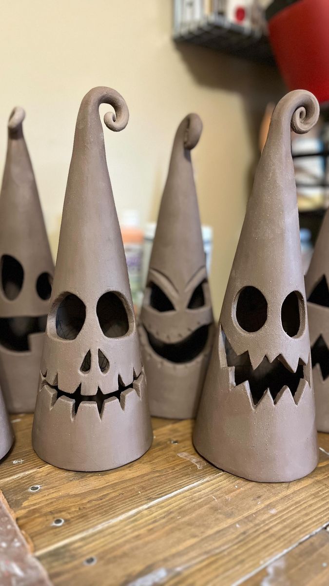 several cement pots with faces painted on them sitting on a wooden table in front of a wall