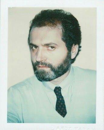 a man with a beard wearing a blue shirt and black tie is looking at the camera