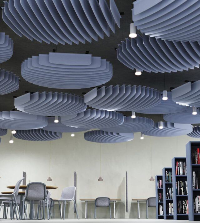 a room filled with lots of chairs and tables under suspended ceiling lights in an office building