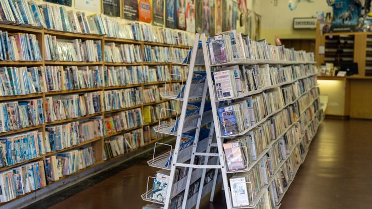 there is a shelf full of dvd's in the store with many shelves on each side