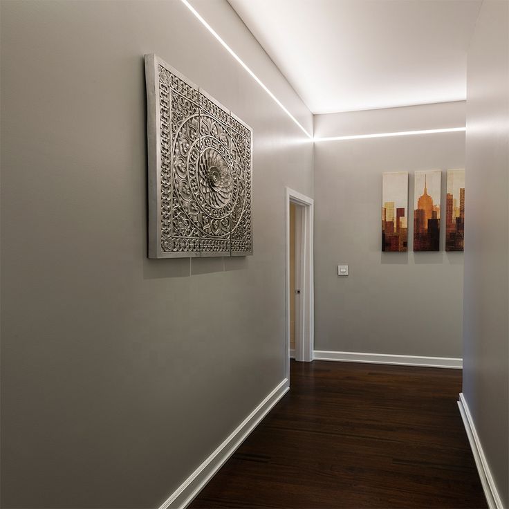 an empty hallway with two paintings on the wall and wood flooring in front of it