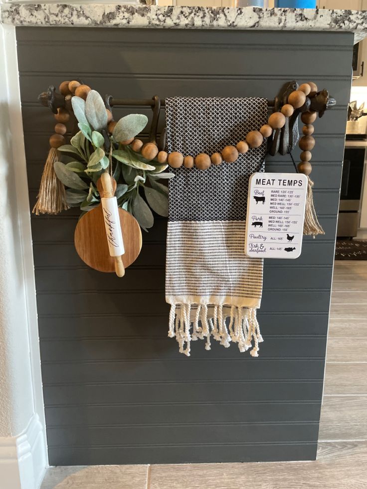 a wall hanging on the side of a kitchen with wooden beads and tassels