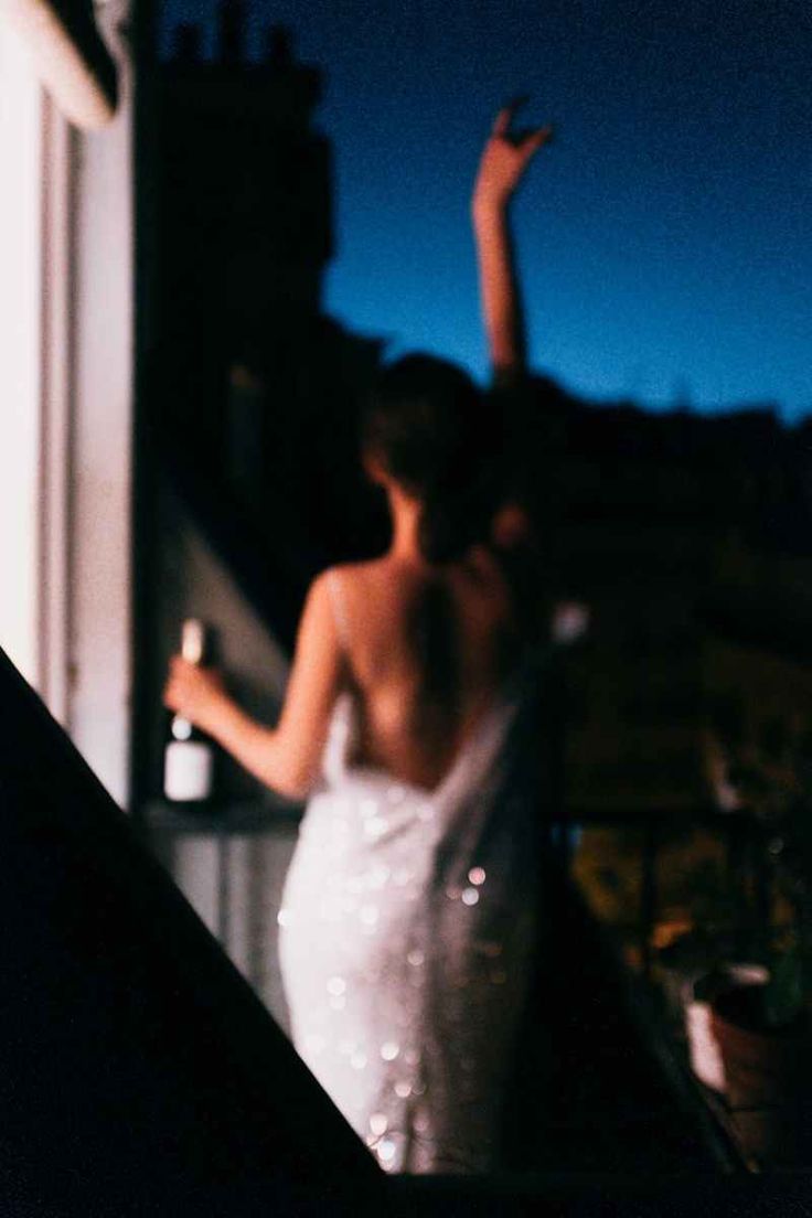 a woman in a white dress standing on top of a balcony next to a building