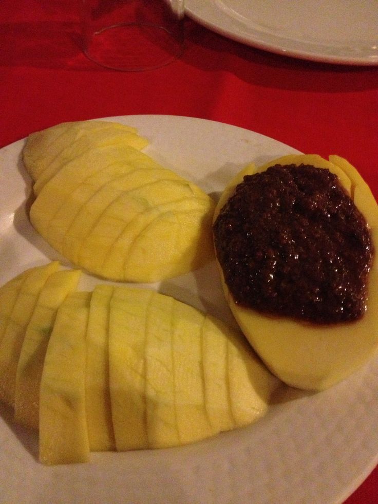 a white plate topped with slices of fruit and sauce on top of each other next to a red table cloth