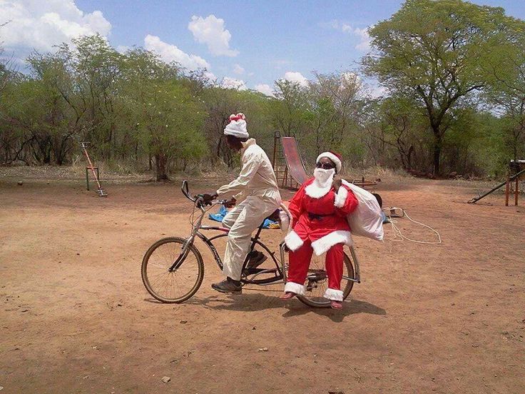 two people dressed as santa clause riding a bike