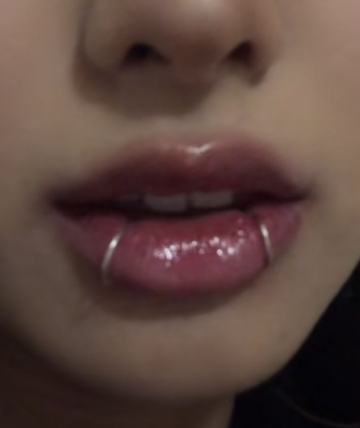 a close up view of a woman's lips with clear, shiny lip rings