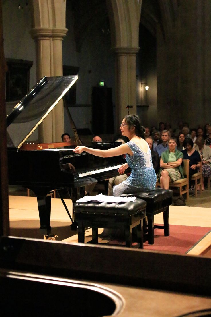 a woman sitting at a piano in front of an audience