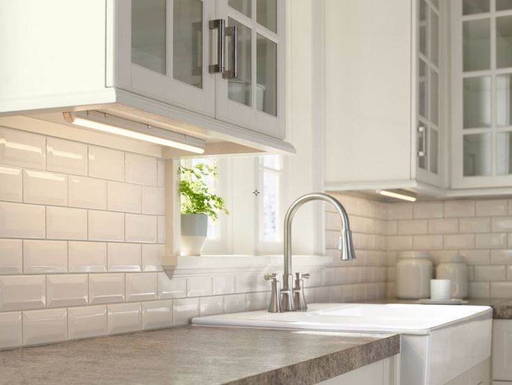 a kitchen with white cabinets and marble counter tops, along with a stainless steel faucet