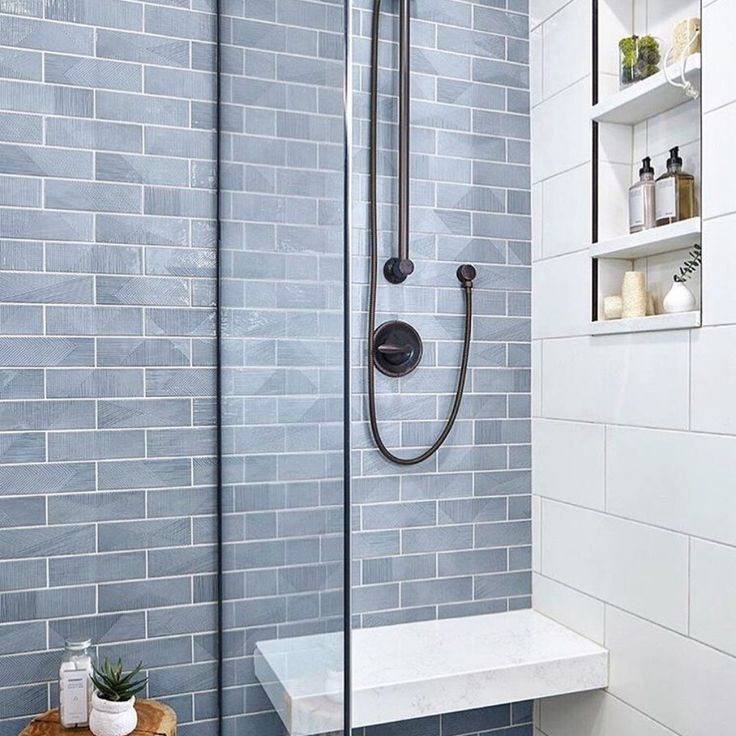 a walk in shower sitting next to a tiled wall