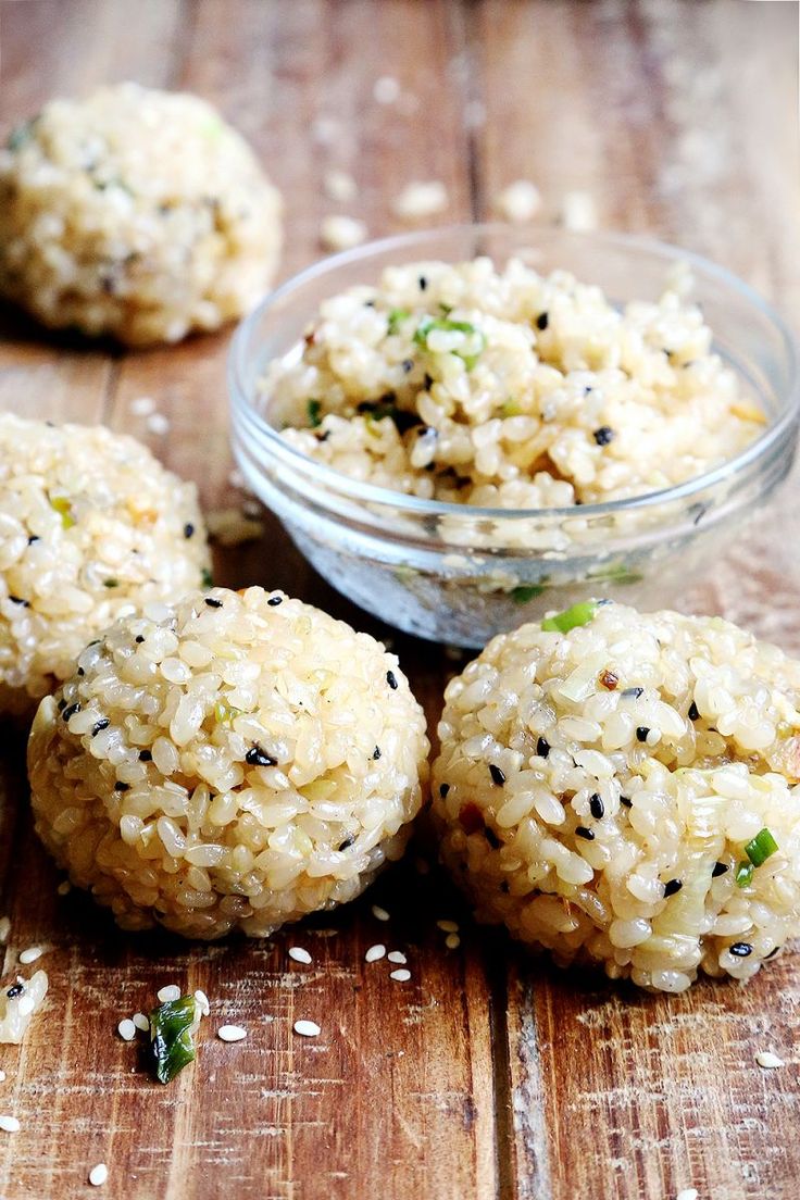 four balls of rice are sitting on a wooden table next to a small glass bowl