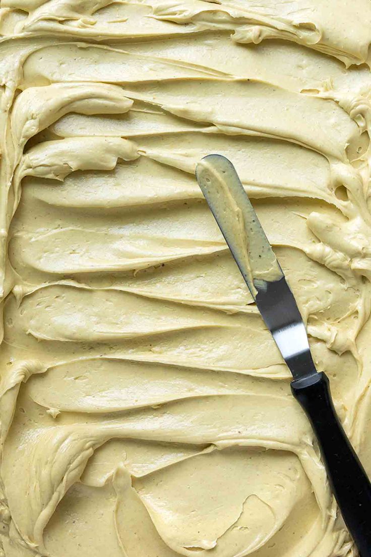 a knife cutting into a cake with frosting on it