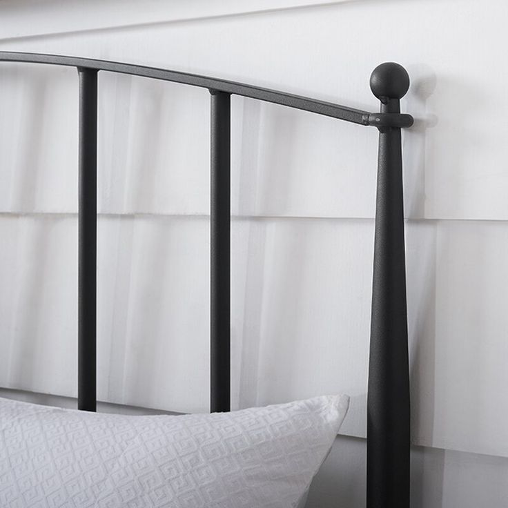 a black metal bed frame with white pillows