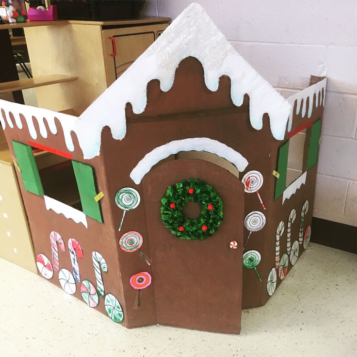 a cardboard gingerbread house with wreath and candy on the front door for christmas decorations