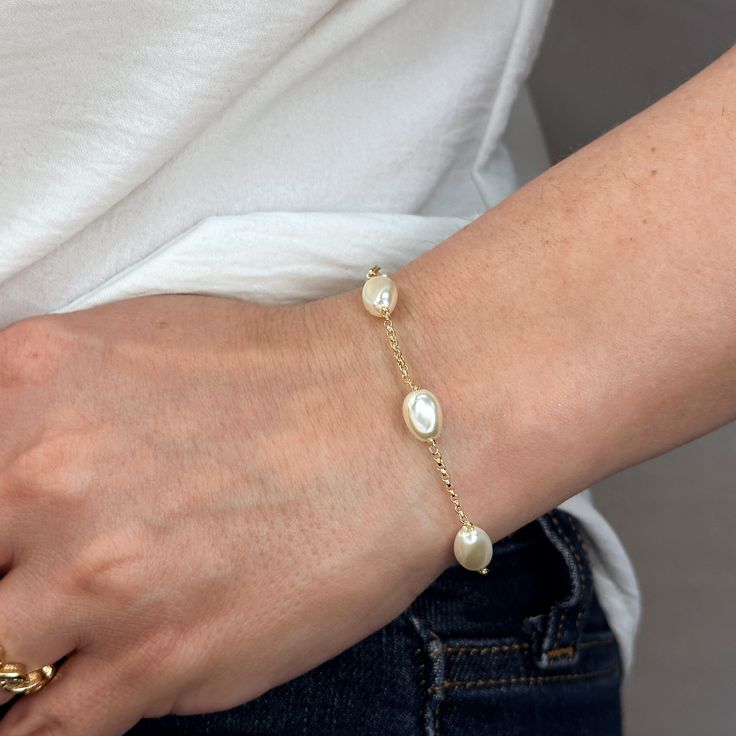 Indulge in the timeless beauty and sophistication of our 18k Gold Filled Spaced Baroque Pearl Bracelet. The perfect blend of elegance and delicacy, this classic piece exudes a luxurious charm that will elevate any outfit. Add a touch of opulence to your wardrobe and captivate with every turn of your wrist. Metal: 18k Gold Filled Width: 10mm Simulated Baroque Pearl Beads Size: 6.5 + 1 inch adjustment. Hypoallergenic Water-resistant Handcrafted in Brazil Formal Yellow Gold Bracelets With Pearl Charm, Formal Yellow Gold Bracelet With Pearl Charm, Formal Gold Bracelet With Pearl Charm, Elegant Pearl Bracelet As Gift, Elegant Pearl Bracelet Jubilee Style As Gift, Luxury Pearl Chain Bracelet For Formal Occasions, Elegant Pearl Jubilee Bracelet Gift, Elegant Adjustable Gold Bracelet With Pearl Charm, Elegant Pearl Charm Bangle Jewelry