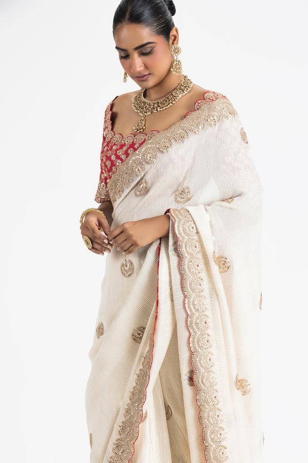 Ivory georgette lurex weave saree with scattered floral butti embroidery. Paired with a padded blouse, embroidered with gota, zari, dabka, beads and resham work.
Components: 2
Pattern: Embroidery
Type Of Work: Floral, Gota, Zari, Dabka, Beads
Neckline: Scoop Neck
Sleeve Type: Half Sleeves
Fabric: Georgette, Brocade
Color: Ivory
Other Details: 
Blouse:
Padded
Scallop trimmed edges
Back tie-up detailing with stones ornamentation
Occasion: Destination Wedding - Aza Fashions White Chikankari Embroidery Blouse For Reception, White Blouse With Chikankari Embroidery For Reception, Elegant Resham Embroidered Slub Silk Pre-draped Saree, Elegant Slub Silk Pre-draped Saree With Resham Embroidery, Off White Blouse Piece For Reception With Traditional Drape, Off White Traditional Drape Blouse Piece For Reception, Elegant Slub Silk Blouse With Dupatta, Elegant Tussar Silk Blouse With Dupatta, Elegant White Chikankari Embroidery Blouse Piece