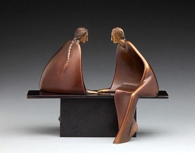 two bronze figurines sitting on top of a black table next to each other