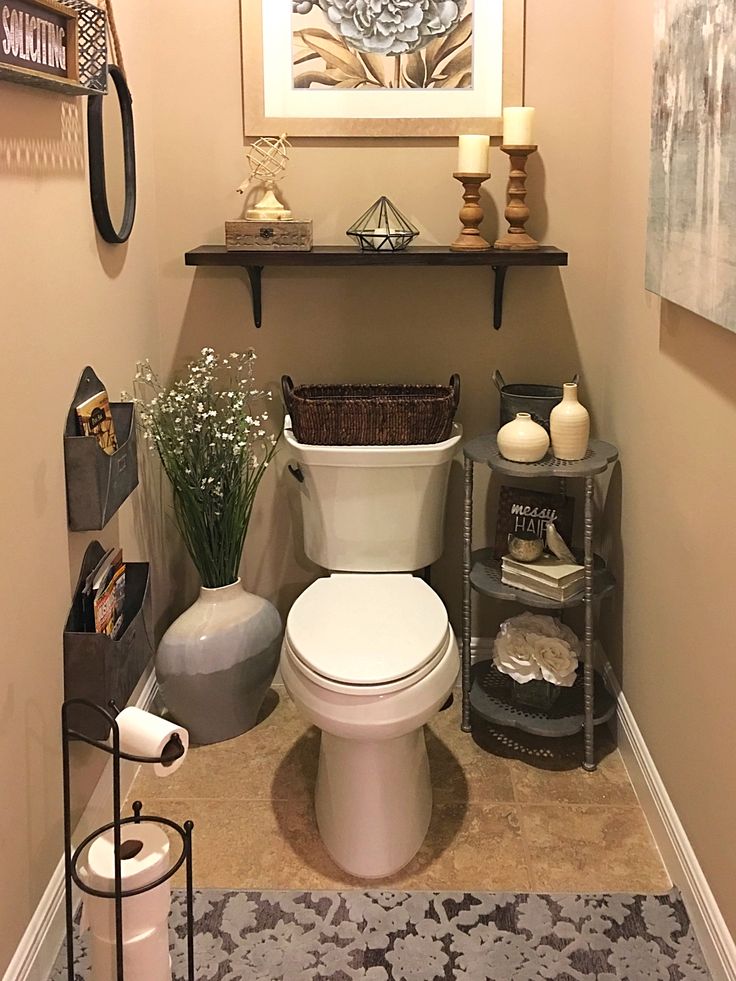 a white toilet sitting in a bathroom next to a shelf filled with vases and candles