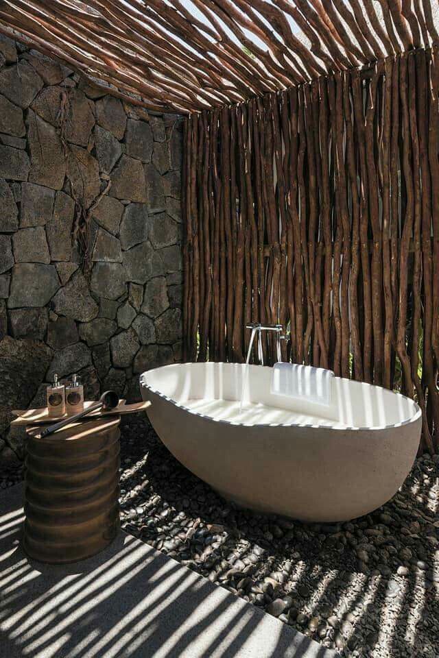 a bathtub sitting in the middle of a room next to a stone wall and floor