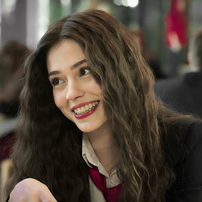 a woman sitting at a table with a plate of food in her hand and smiling