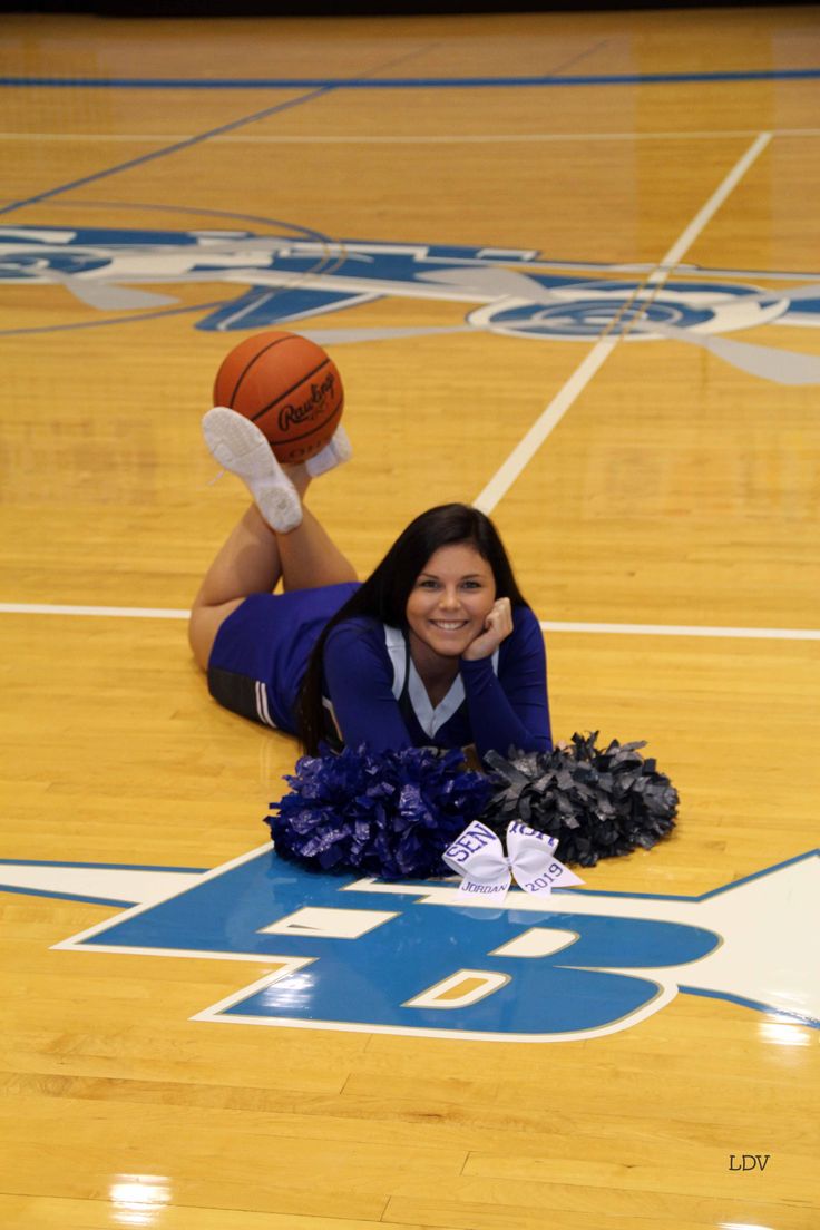 a woman laying on the floor with a basketball and pom poms in front of her