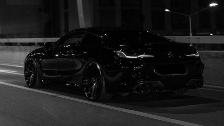 a black sports car driving down the road at night