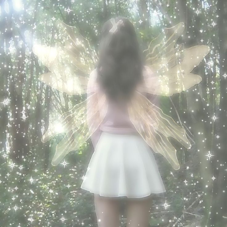 a girl in a white dress with wings on her back standing in front of trees