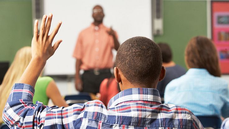 a group of people sitting in front of a class room with their hands raised up