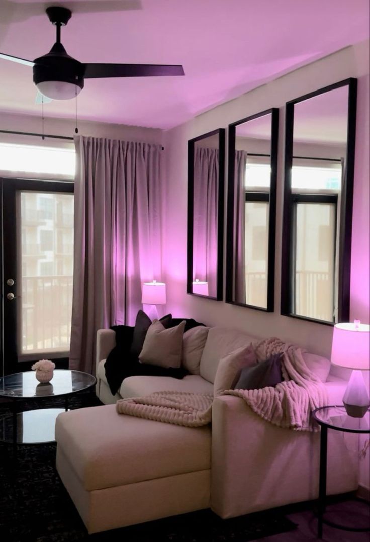 a living room filled with furniture and purple lighting on the walls, along with large windows