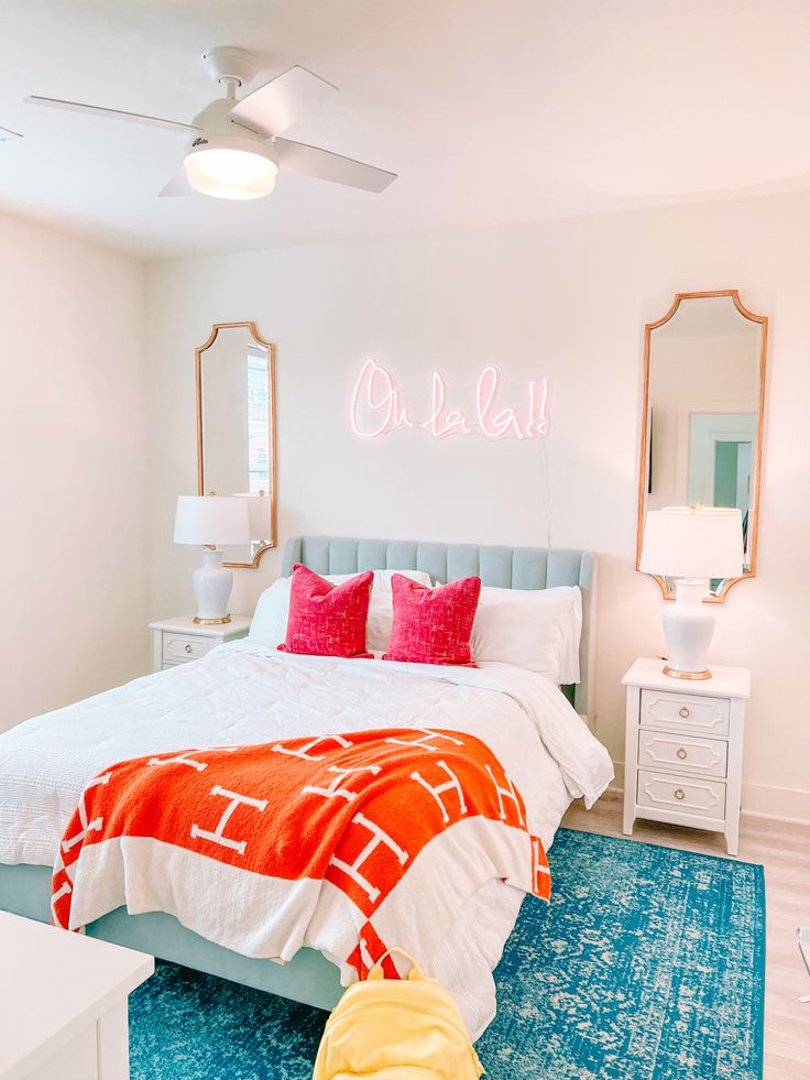 a bedroom with a bed, dresser and mirror on the wall that says oh la la