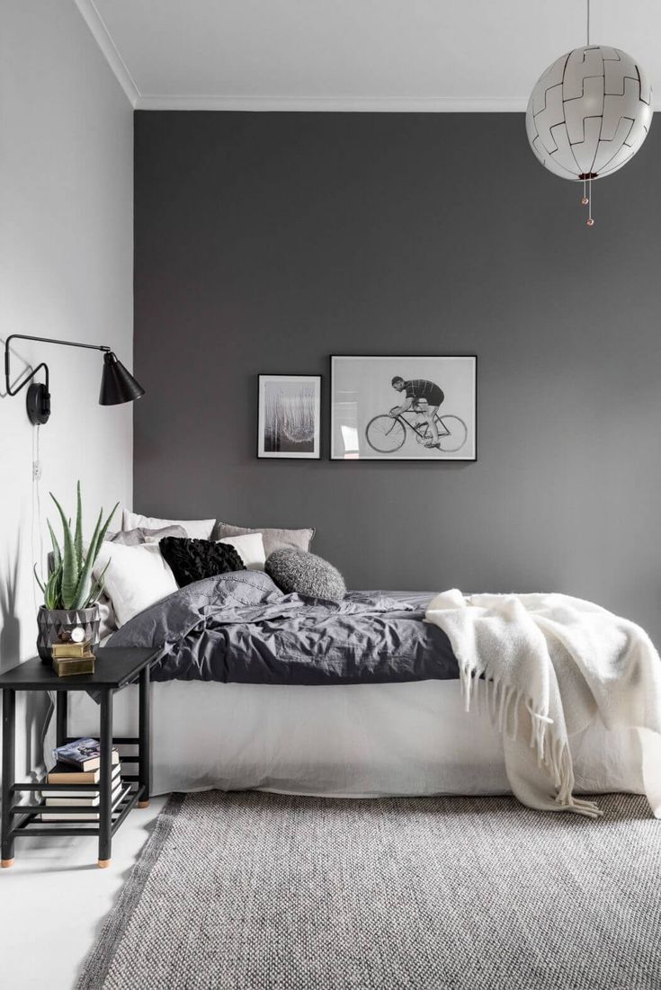 a bedroom with grey walls and white bedding in the center, along with a rug on the floor