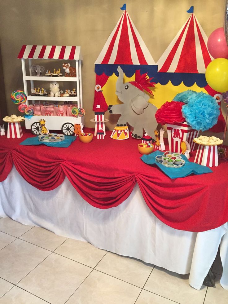 a circus themed birthday party with red and white decorations, balloons, and food on a table