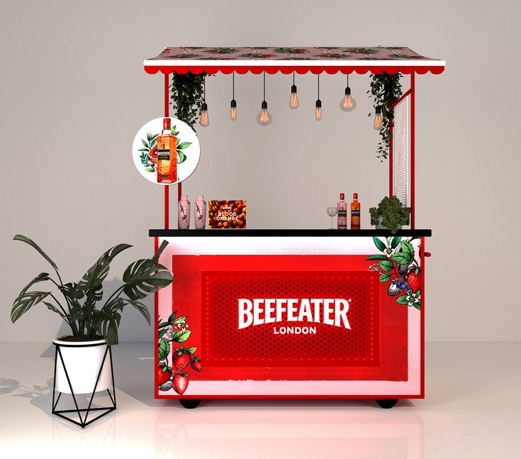 a red and white food cart sitting next to a potted plant